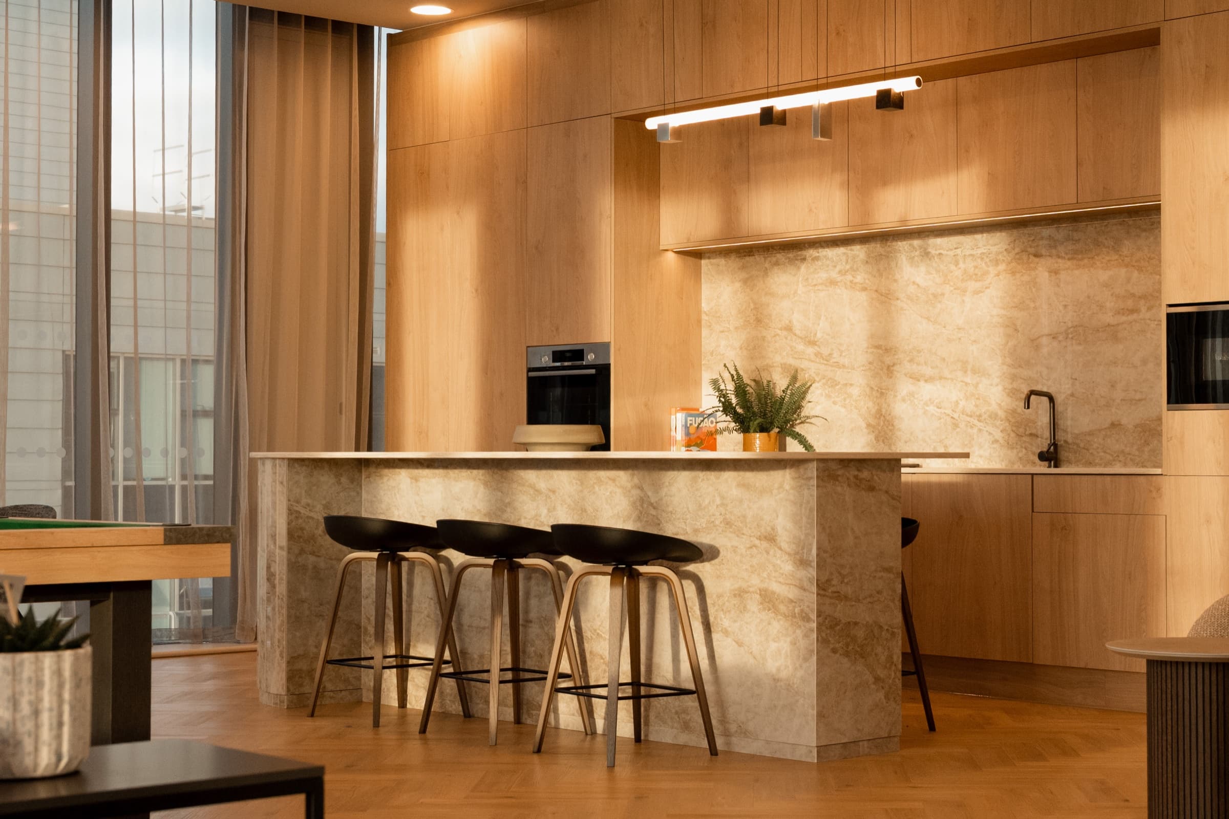 Kitchen with a marble-clad island, bar stools and a marble splashback