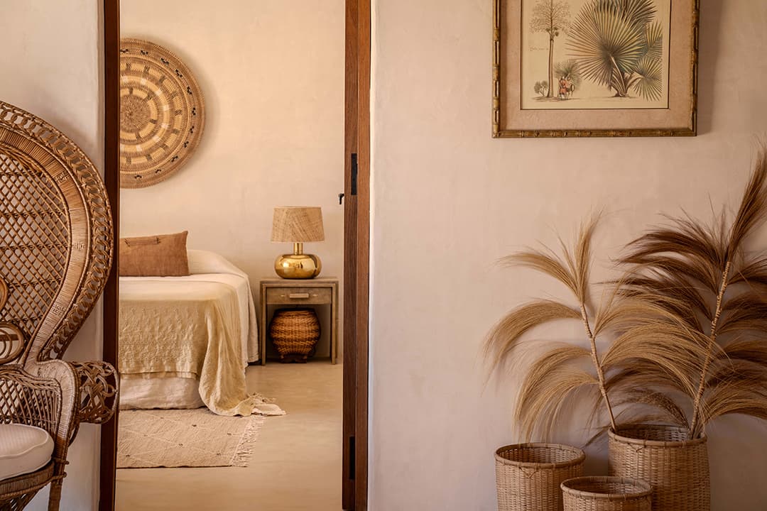 Bedroom interior styled with rattan furniture, seen through an open doorway