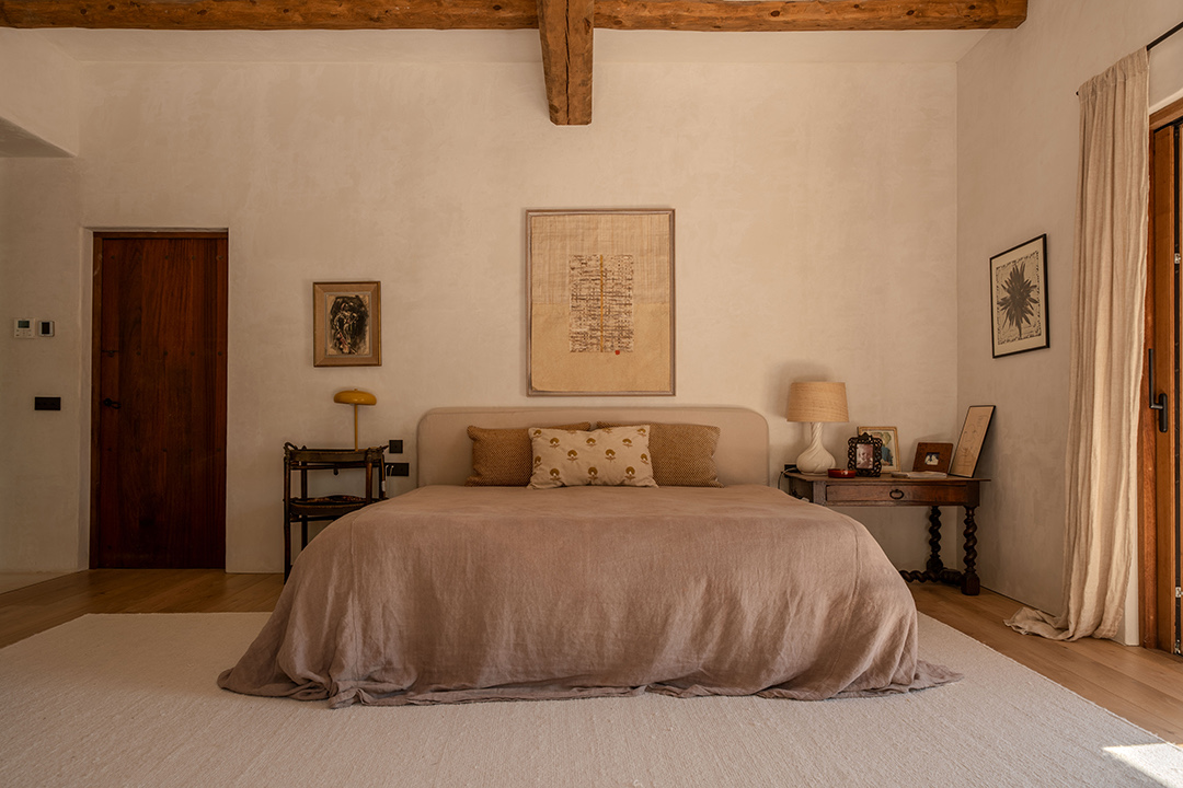 Bedroom with an exposed wooden ceiling beam and neutral linen bedding